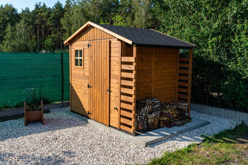 A wooden garden shed standing on a concrete foundation in a garden.