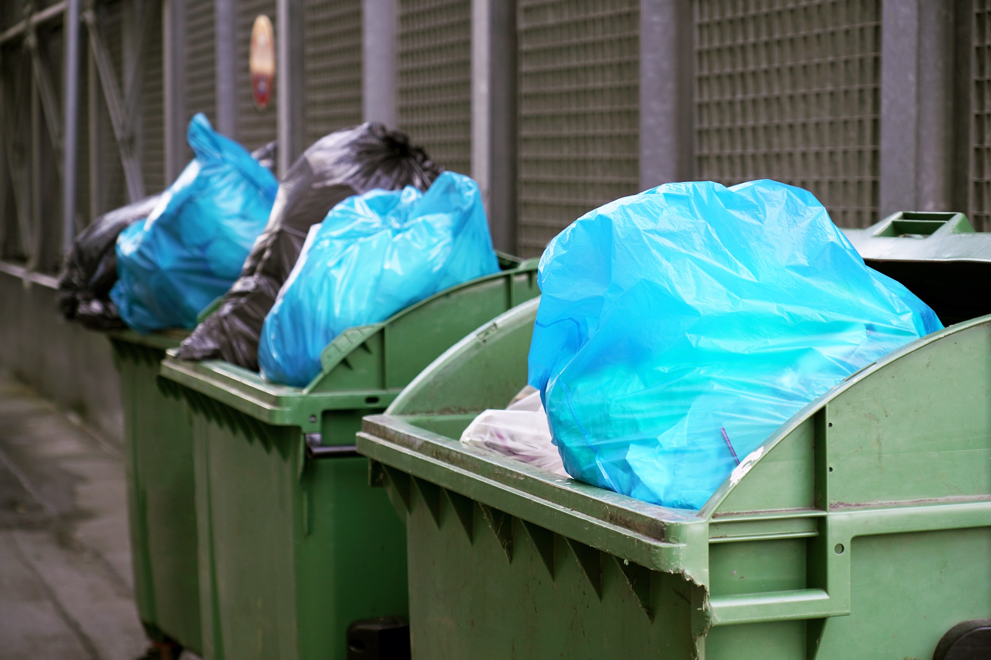 dumpster or refuse container overflowing with trash in garbage bags