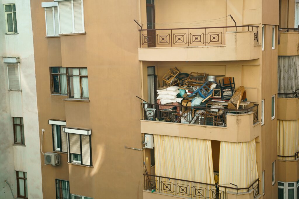 Ugly, terrible balcony disorder. Multi-storey building full of garbage, old furniture, unnecessary