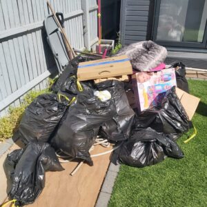 Before: pile of black rubbish bags and boxes in a back garden
